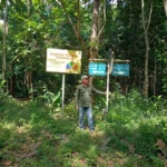 Petugas Polisi Kehutanan berseragam lapangan hijau menunjuk papan peringatan daerah rawan terbakar saat patroli pengamanan di kawasan hutan Resor Kucur.