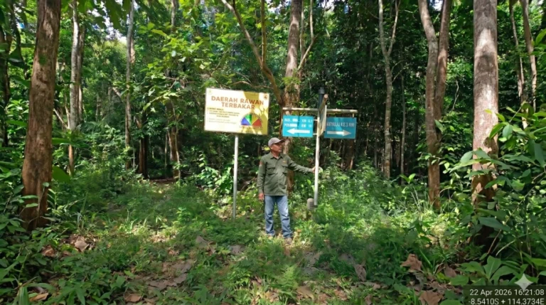 Petugas Polisi Kehutanan berseragam lapangan hijau menunjuk papan peringatan daerah rawan terbakar saat patroli pengamanan di kawasan hutan Resor Kucur.