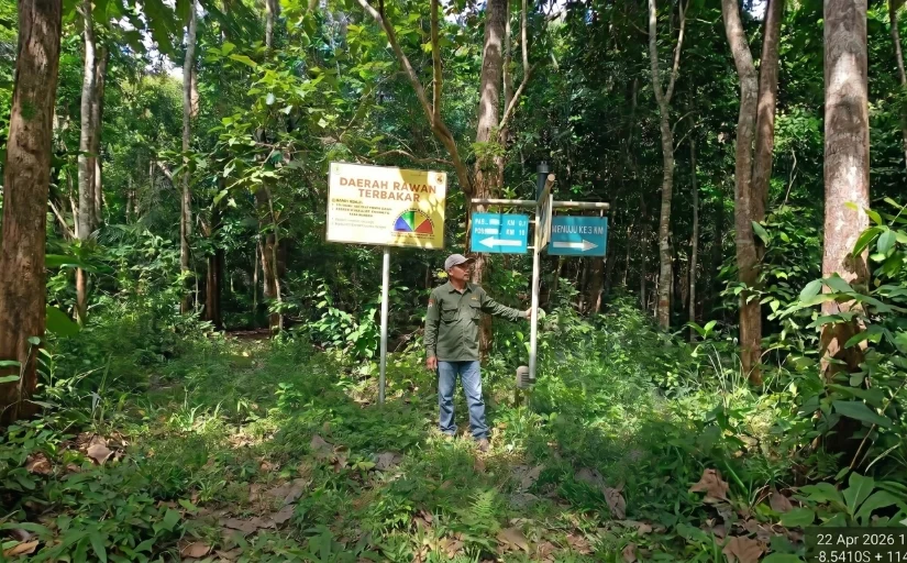 Petugas Polisi Kehutanan berseragam lapangan hijau menunjuk papan peringatan daerah rawan terbakar saat patroli pengamanan di kawasan hutan Resor Kucur.