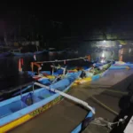 Barisan perahu nelayan tradisional dengan katir tertambat di dermaga Taman Nasional Alas Purwo pada malam hari.