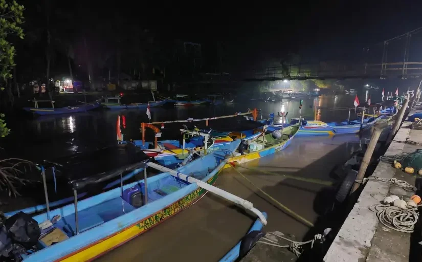 Barisan perahu nelayan tradisional dengan katir tertambat di dermaga Taman Nasional Alas Purwo pada malam hari.