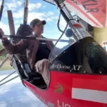 Pesawat microlight patroli udara TN Alas Purwo terparkir di hanggar Resor Kucur, menunjukkan pilot di kokpit dengan latar belakang lapangan terbang.