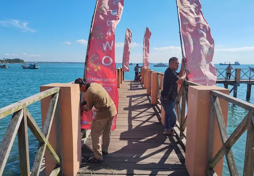 Petugas memasang umbul-umbul di dermaga sebagai bagian dari persiapan petik laut Resor Sembulungan